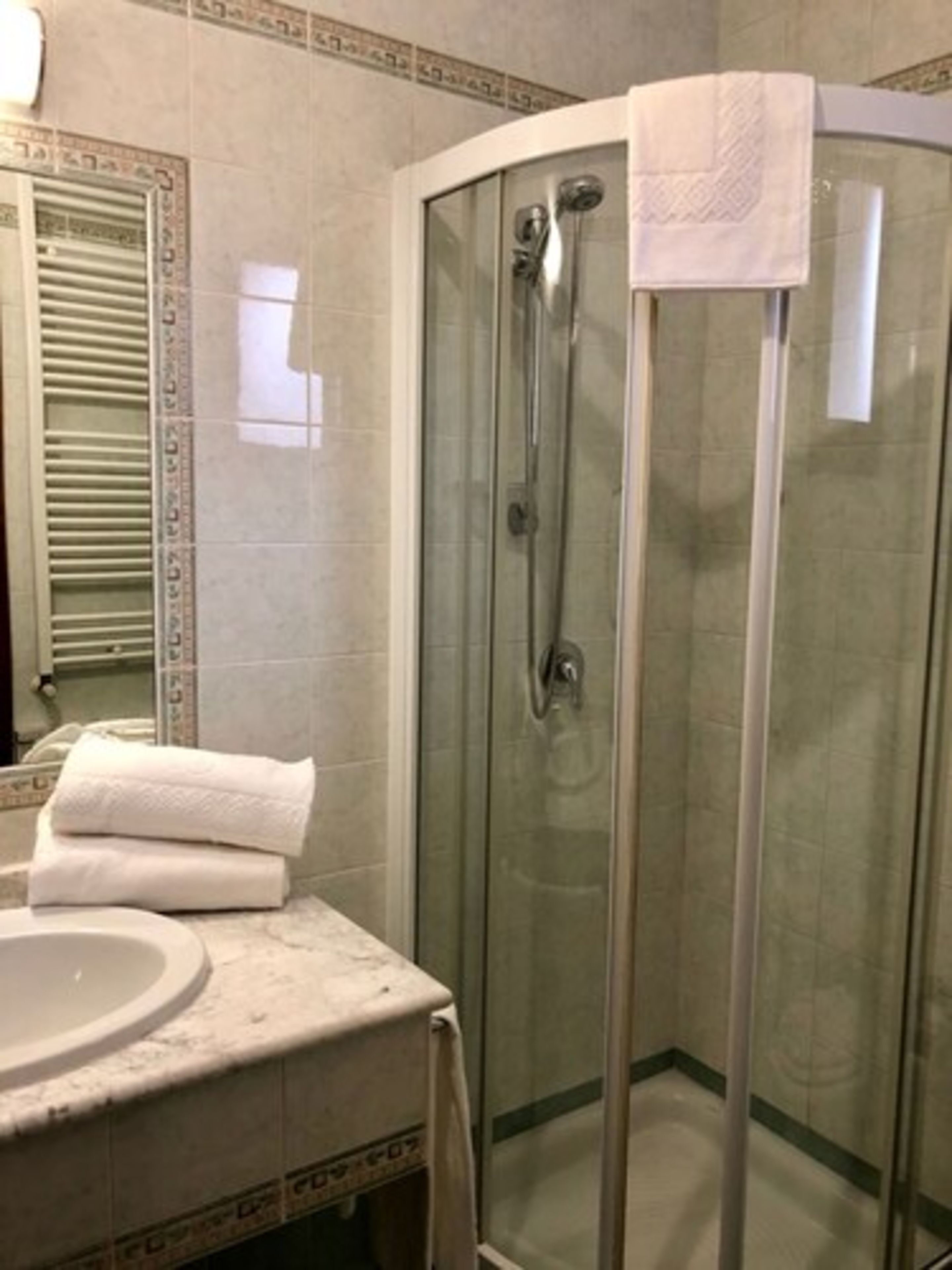 A bathroom with a glass-enclosed shower, a sink, and a towel on the counter.