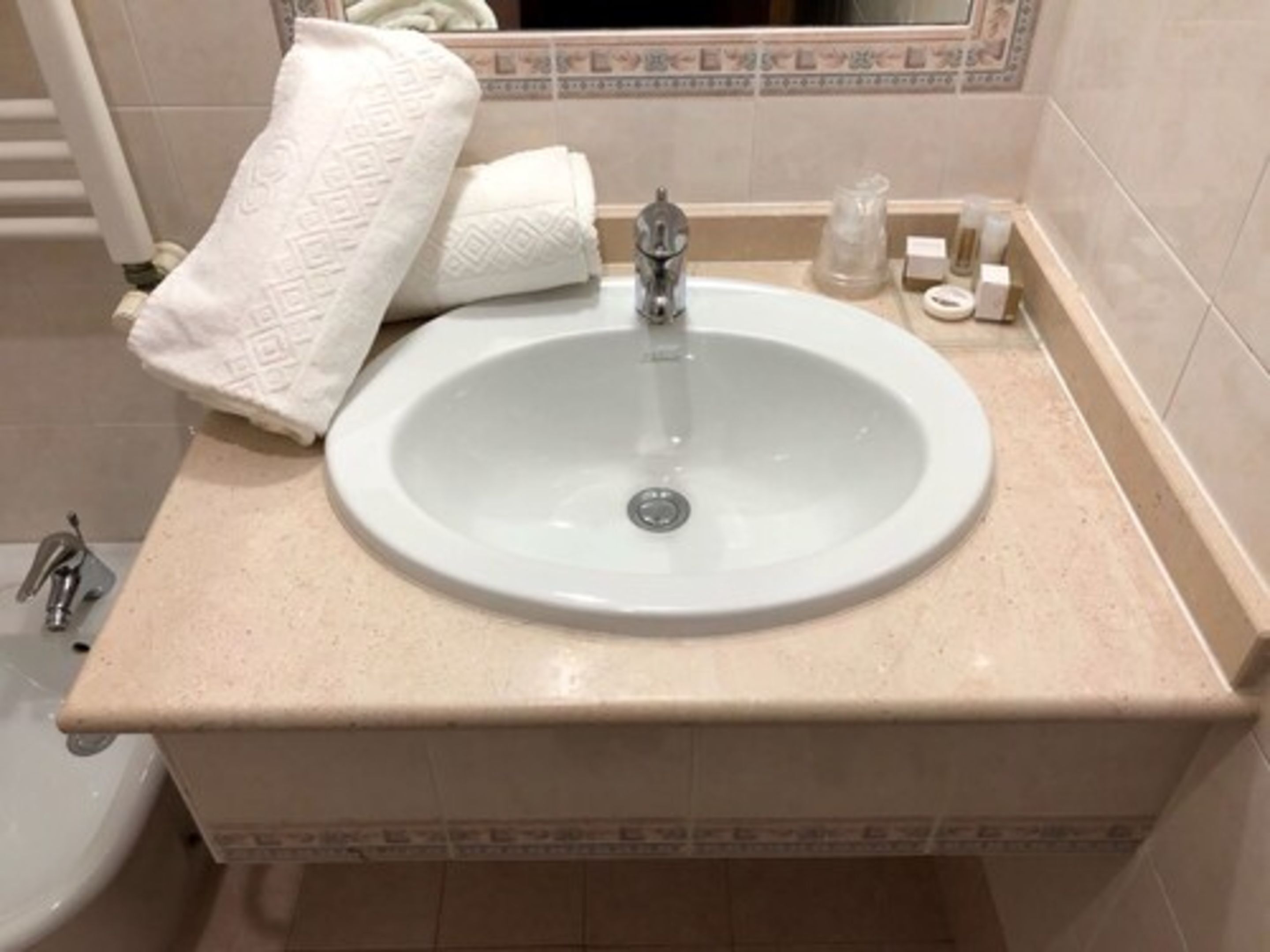 Un baño con lavamanos blanco, una toalla y dispensador de jabón.