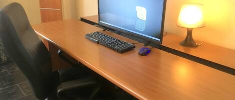 A wooden desk with a computer, keyboard, and mouse.