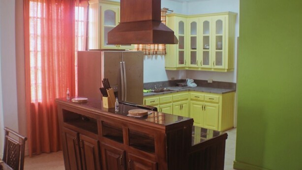A kitchen with wooden cabinets, a central island, and a window with curtains.