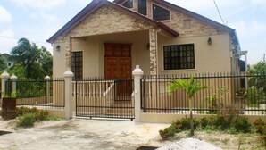 A two-story house with a stone facade, a wooden front door, and a black metal fence.