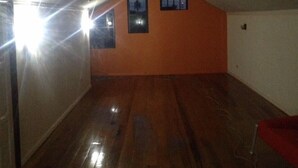 A room with wooden flooring, a sloped ceiling, and two windows with night lights.