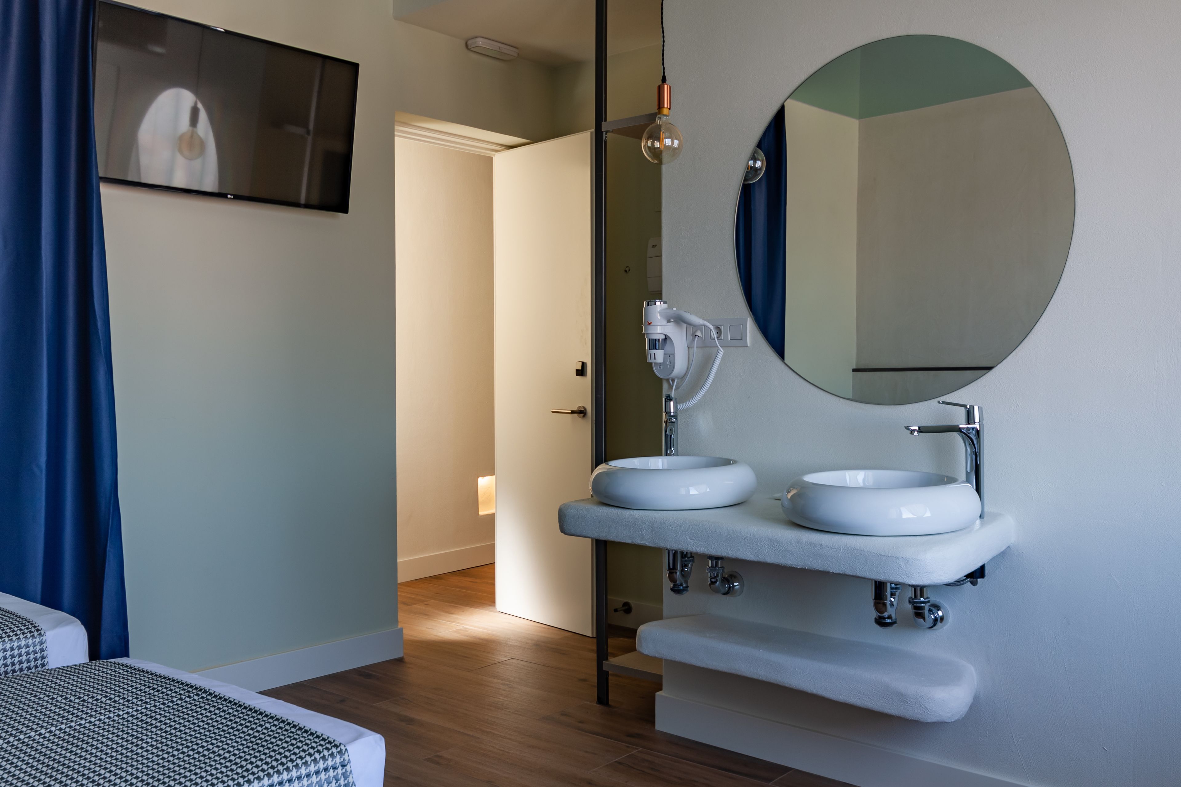 Ein modernes Badezimmer mit einem großen Spiegel, zwei Waschbecken und einem Fön.