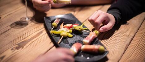 A wooden table with skewers of food and a glass of drink.