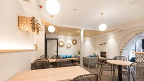 Un área de comedor moderna con mesas y sillas de madera, un sofá y arte decorativo en la pared.