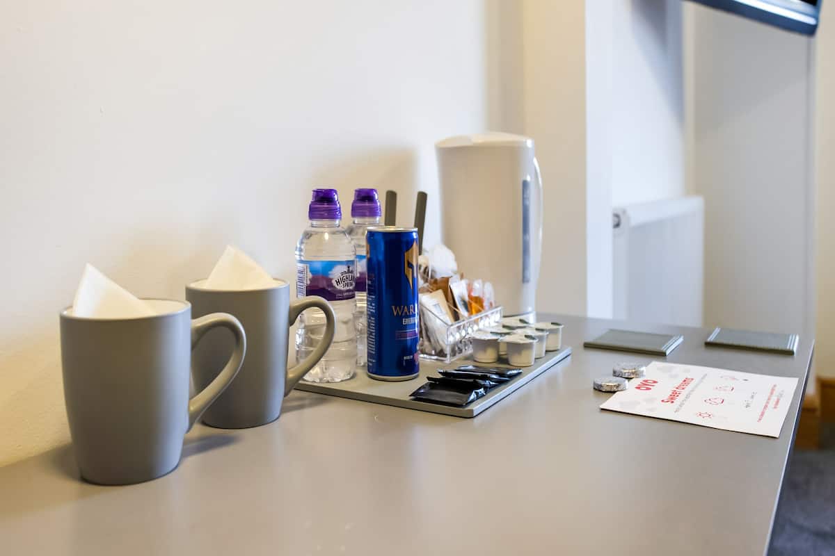 A hotel reception desk with a coffee machine, water bottles, a mug, and a menu.