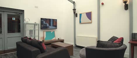 A modern living room with a flat-screen TV, comfortable seating, and a radiator.