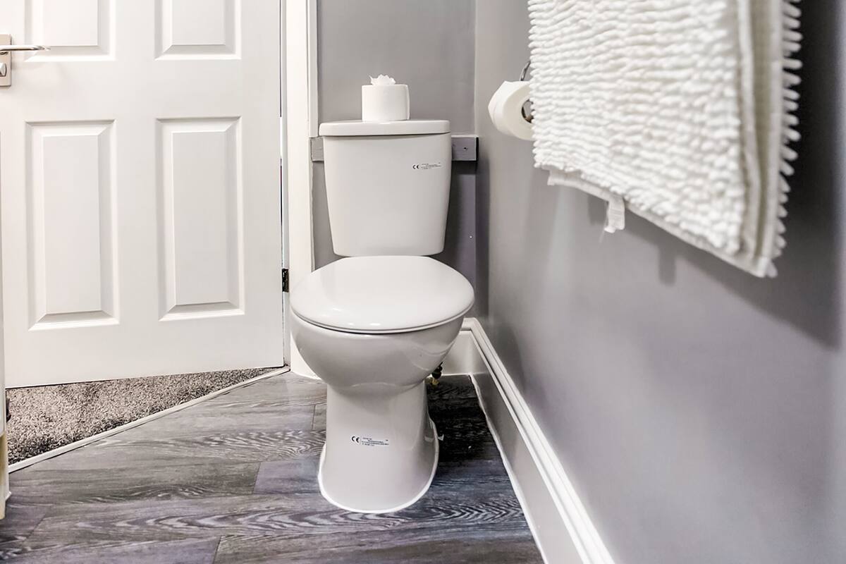 A bathroom with a toilet, white door, and a towel hanging on the wall.