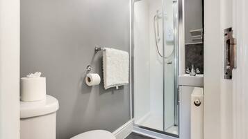 A modern bathroom with a toilet, a shower enclosure, and a towel rack.
