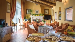 Una sala de estar acogedora con chimenea, asientos cómodos y una mesa llena de diversos postres.