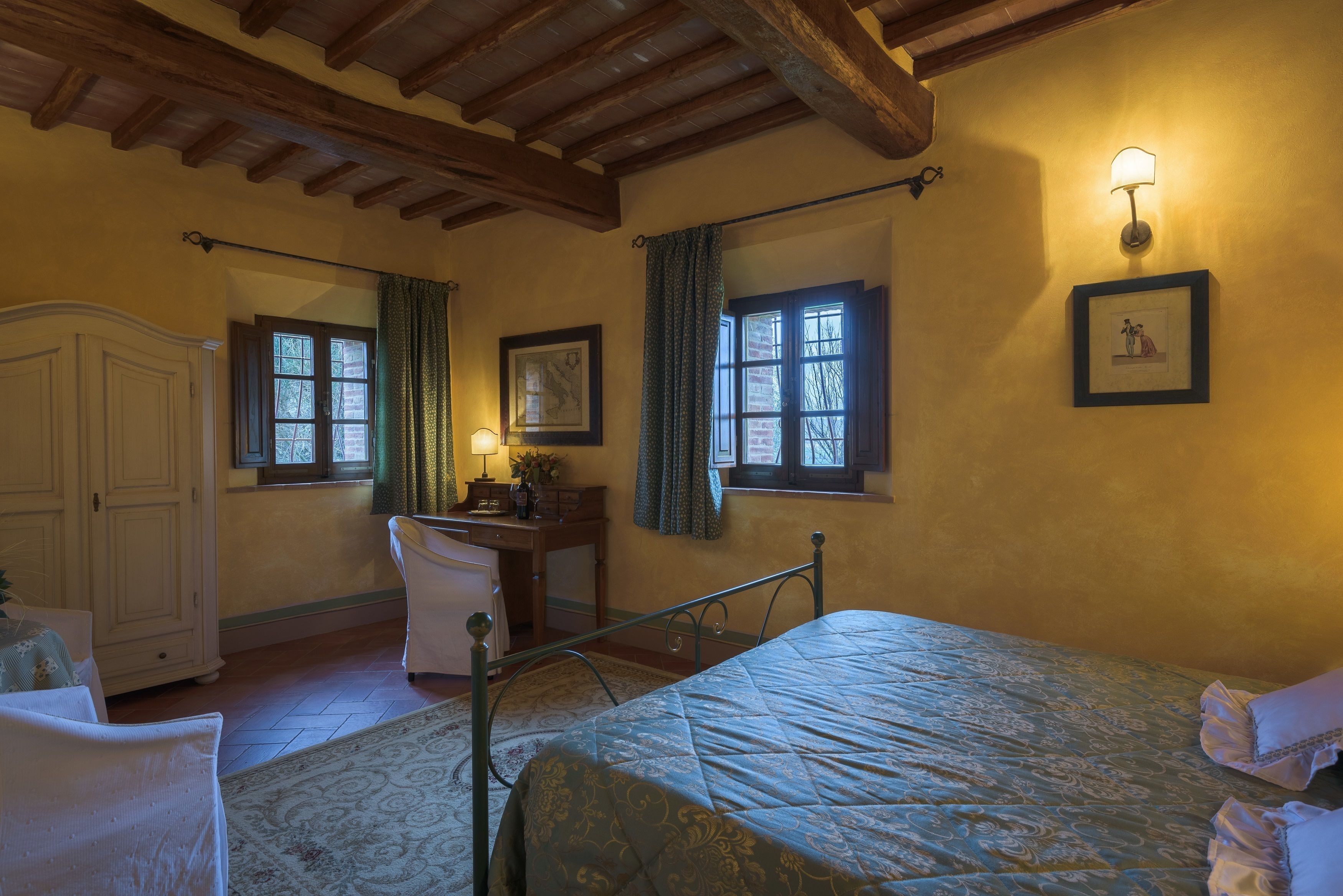 Un dormitorio con cama, escritorio, silla, armario y ventana con cortinas.