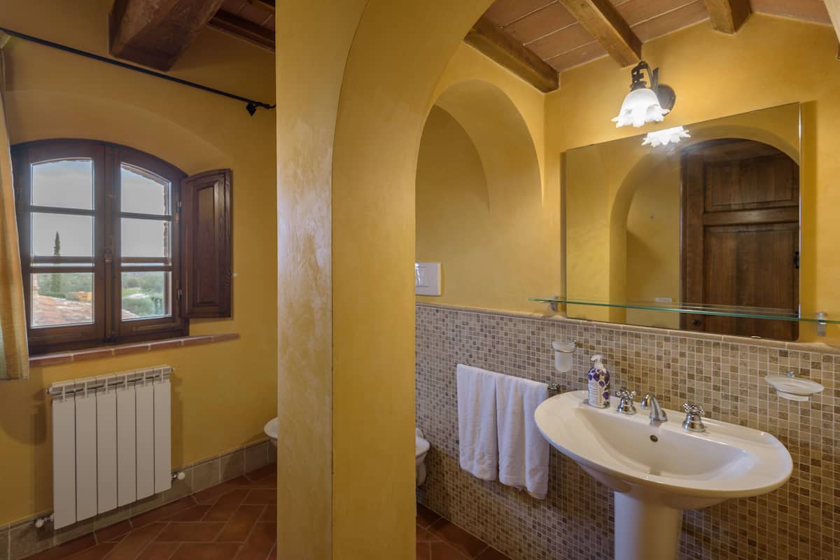 A bathroom with a large window, a sink, and a mirror.