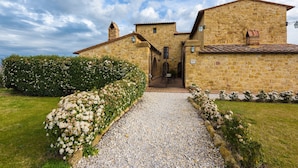 A stone building with a gravel pathway leading to the entrance. - Agriturismo Il Macchione (Pienza)