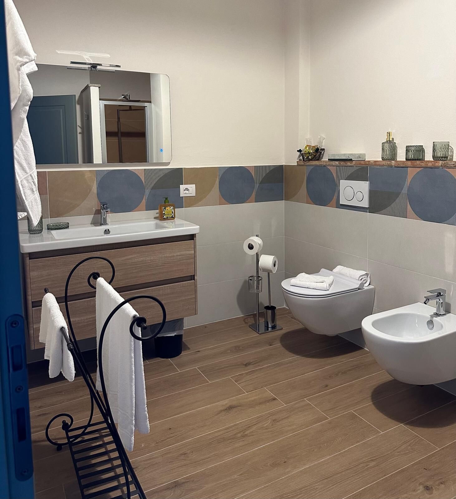 A modern bathroom with a wooden vanity, a toilet, and two sinks.