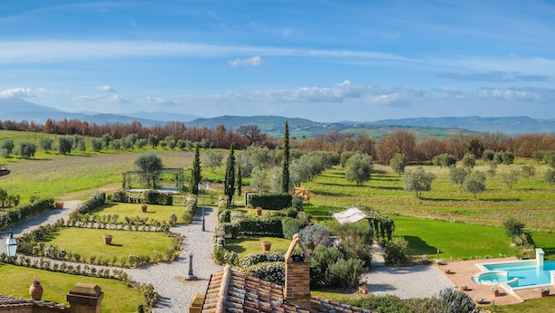 Una villa con piscina, jardín en terrazas y vistas a montañas distantes.