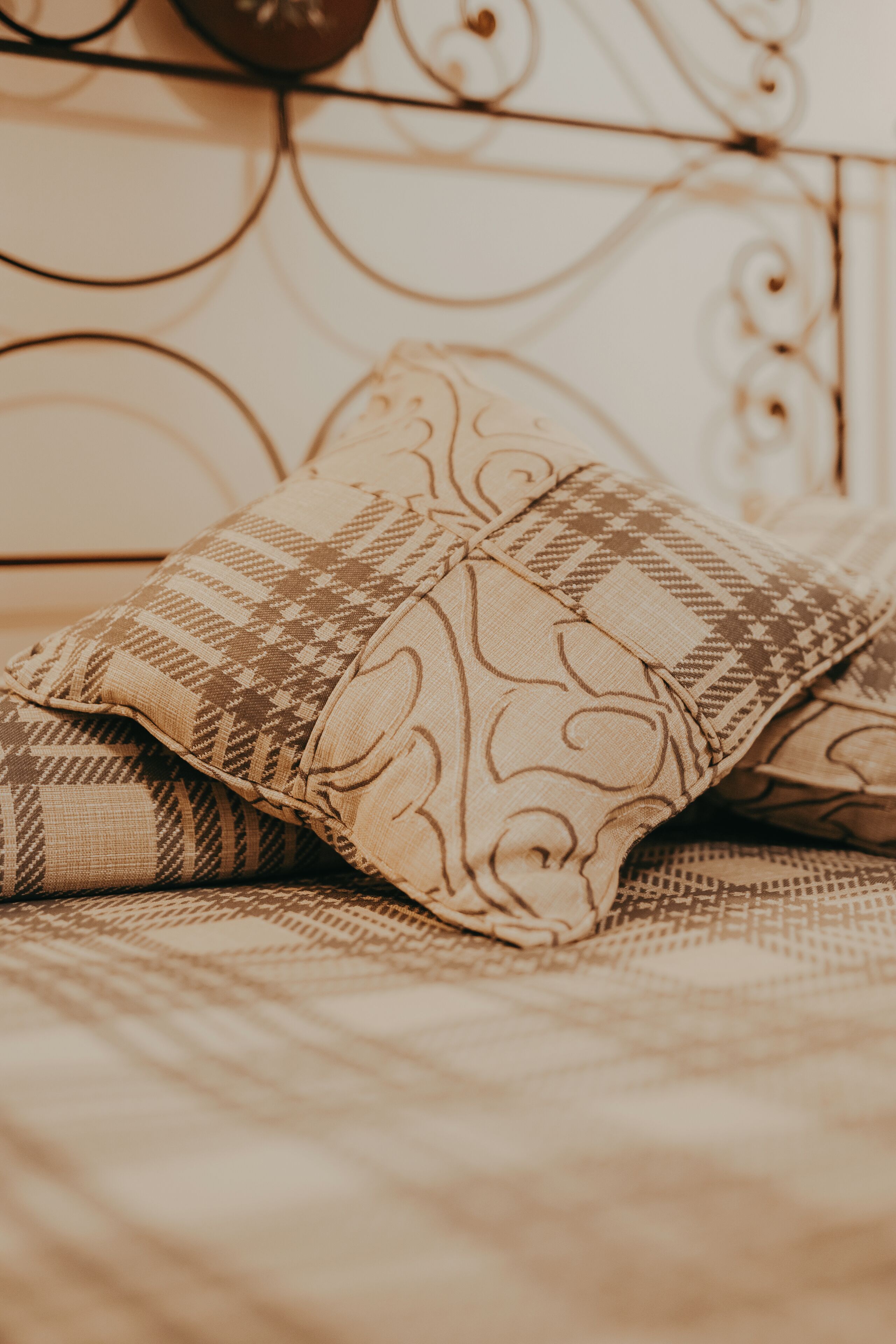 Una cama con almohadas estampadas y cabecera de metal.