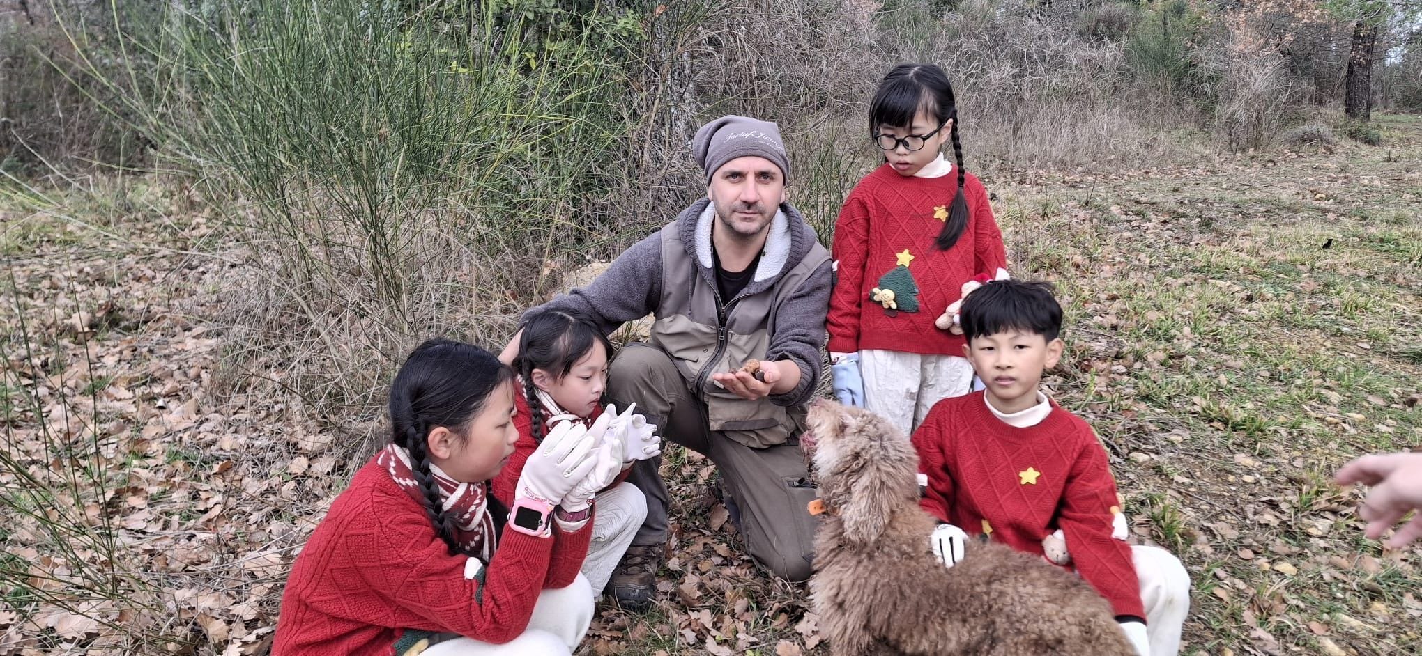 A group of people outdoors in a natural setting with trees and foliage.