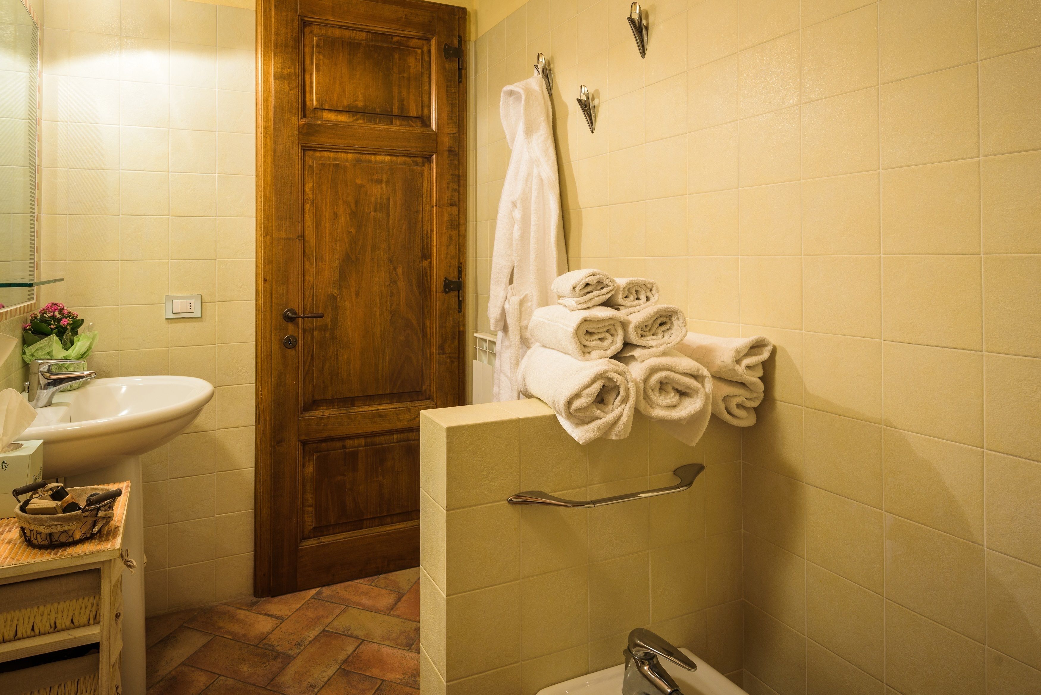 Un baño con puerta de madera, un lavabo, un perchero con toallas dobladas y una zona de ducha.