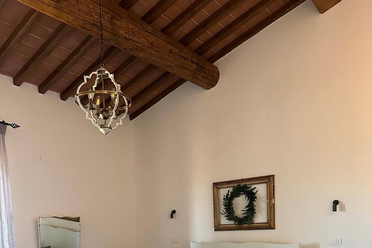 A bedroom with a bed, bedside tables, a desk, chairs, a mirror, and a chandelier.