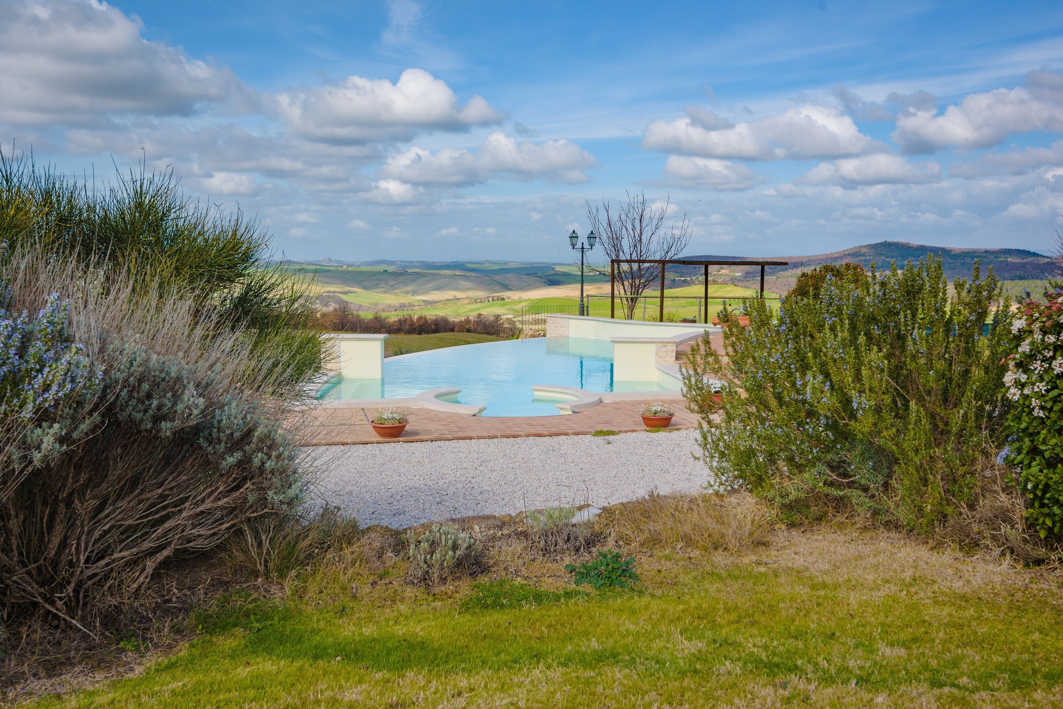 A pool with a view of rolling hills and a clear sky.