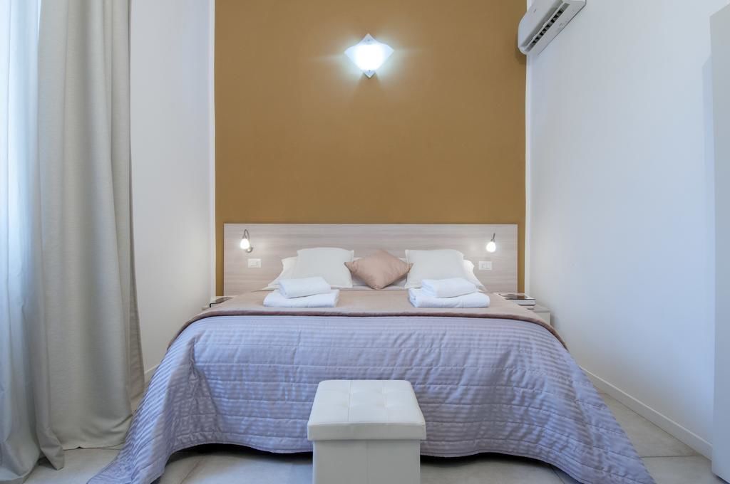 Una cama bien hecha con cabecera, dos lámparas de mesita de noche y una mesita con lámpara.
