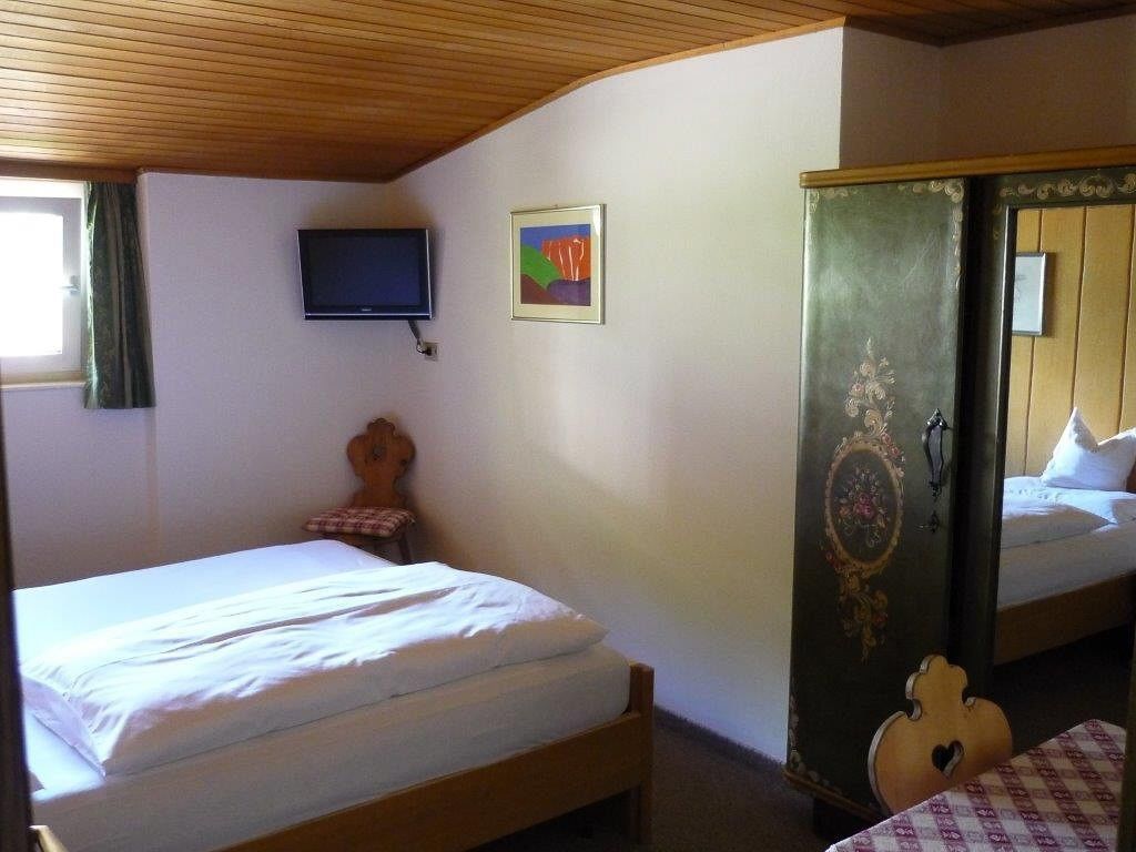 Een kamer met twee bedden, een televisie, een schilderij en een kledingkast.