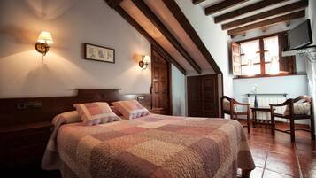 A cozy bedroom with a large bed, wooden headboard, two wall-mounted lamps, and a window with curtains.