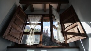 Una stanza con soffitto spiovente e un'ampia finestra con persiane di legno.