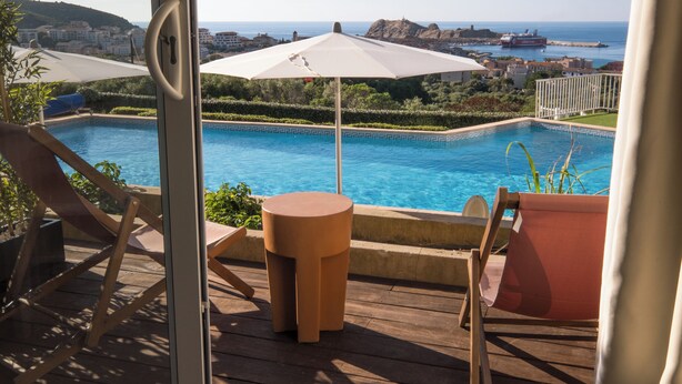 Un espace aménagé au bord de la piscine, avec vue sur la mer, une piscine et un paysage urbain en arrière-plan.