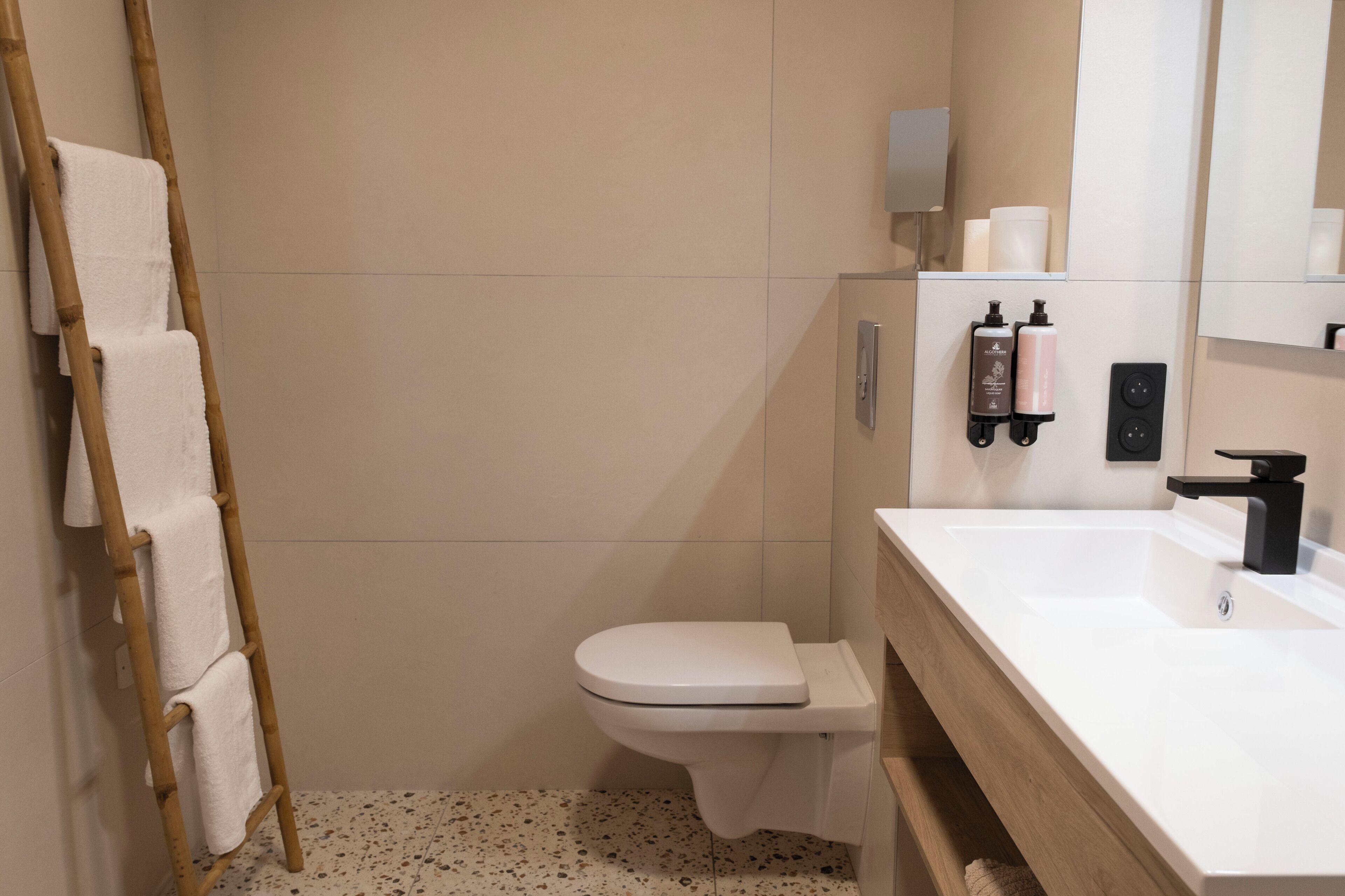 A modern bathroom with a toilet, a sink, a mirror, and a towel rack.