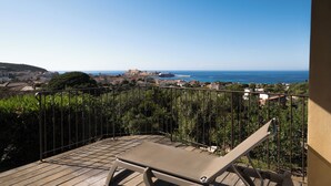 Un balcon avec vue sur la mer et un affleurement rocheux situé au loin.