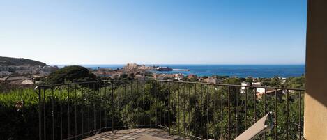 Un balcone con vista sul mare e un promontorio roccioso in lontananza.