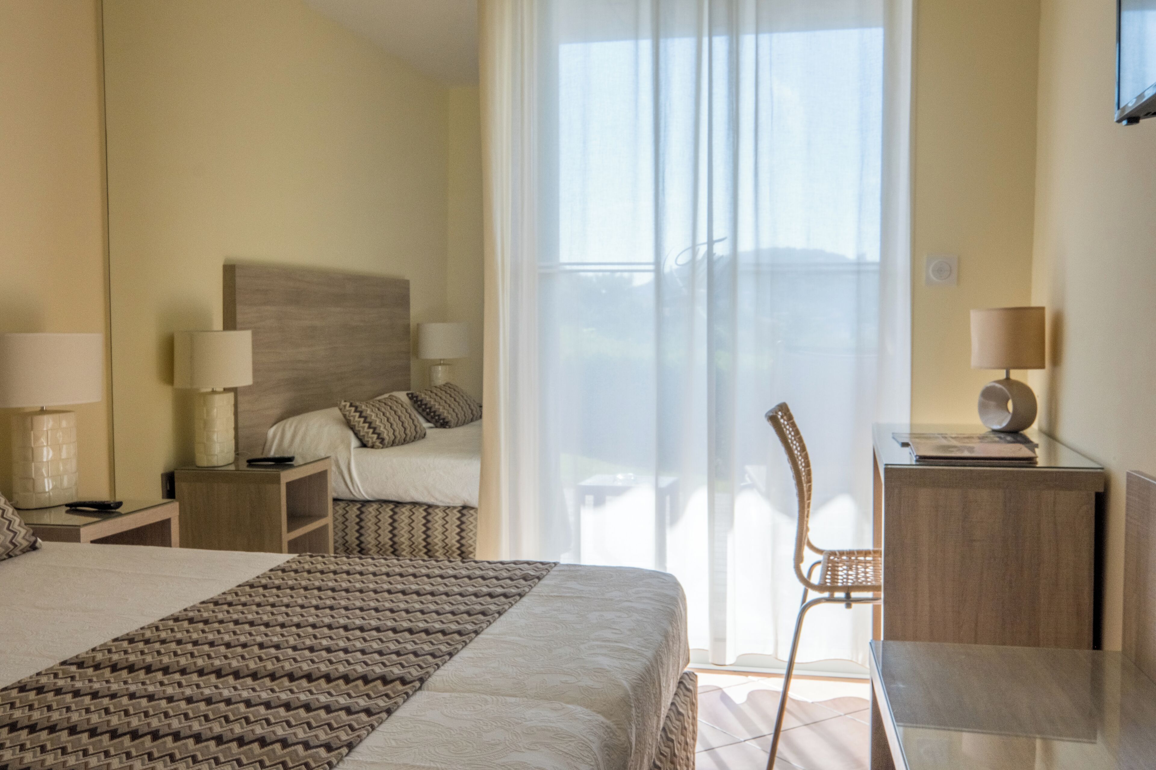 Une chambre d’hôtel avec un grand lit, un bureau, une chaise et une fenêtre avec des rideaux.