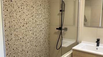A modern bathroom with a shower, a sink, and a mirror.