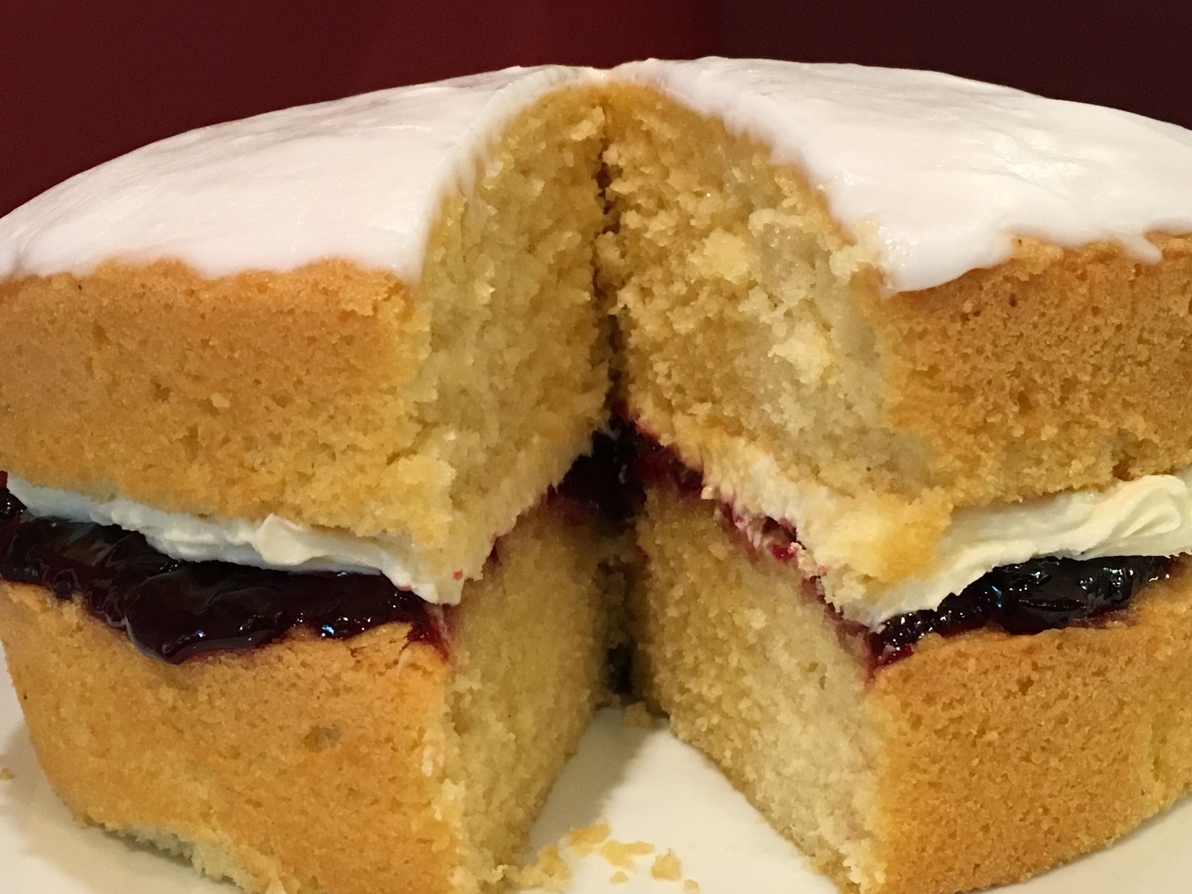 A cake with white icing and a dark filling, cut in half.