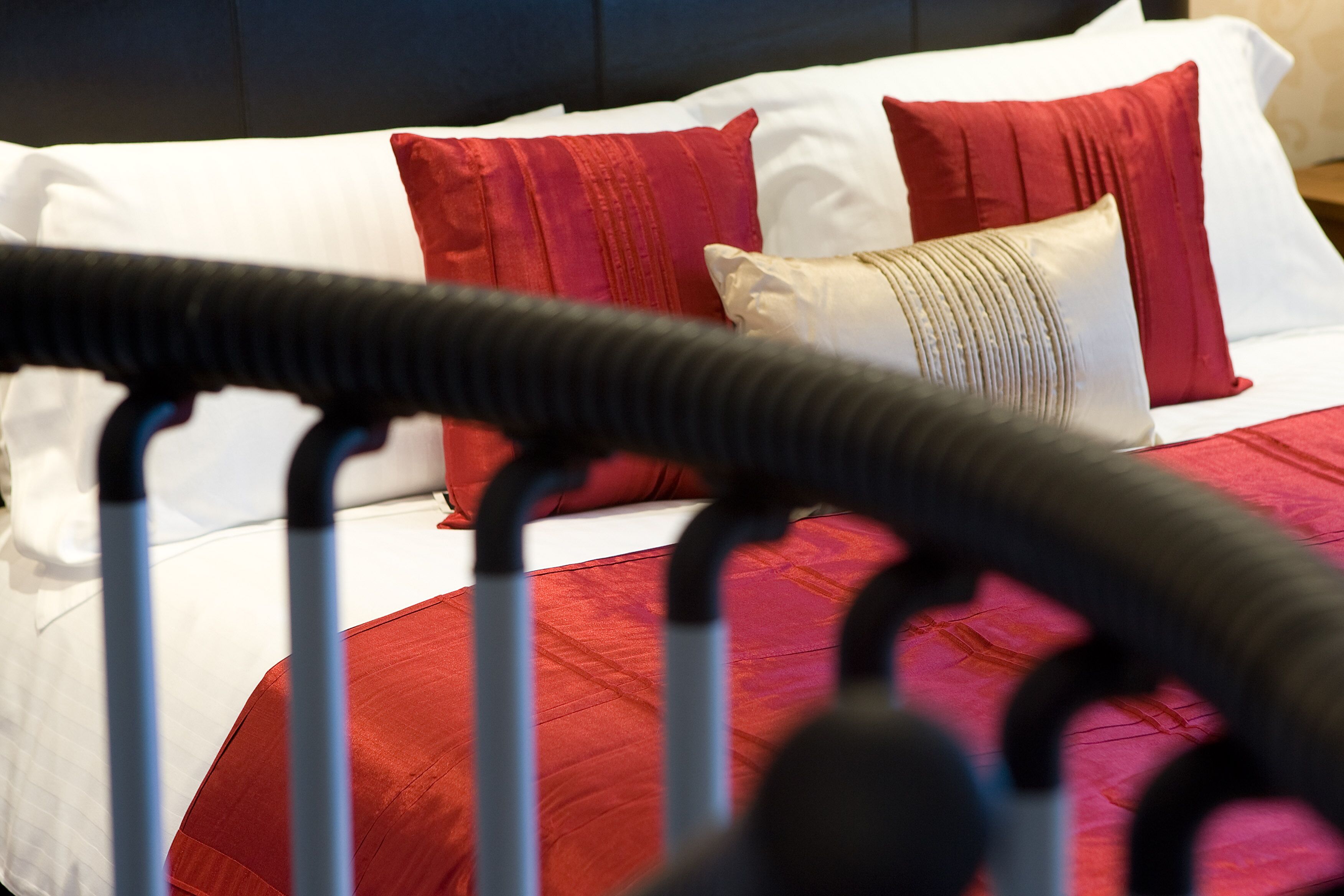 A bed with red and white bedding, a black headboard, and a red and white striped pillow.