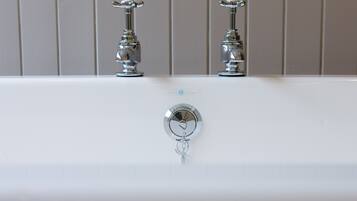 A bathroom with two chrome faucets and a single handle.