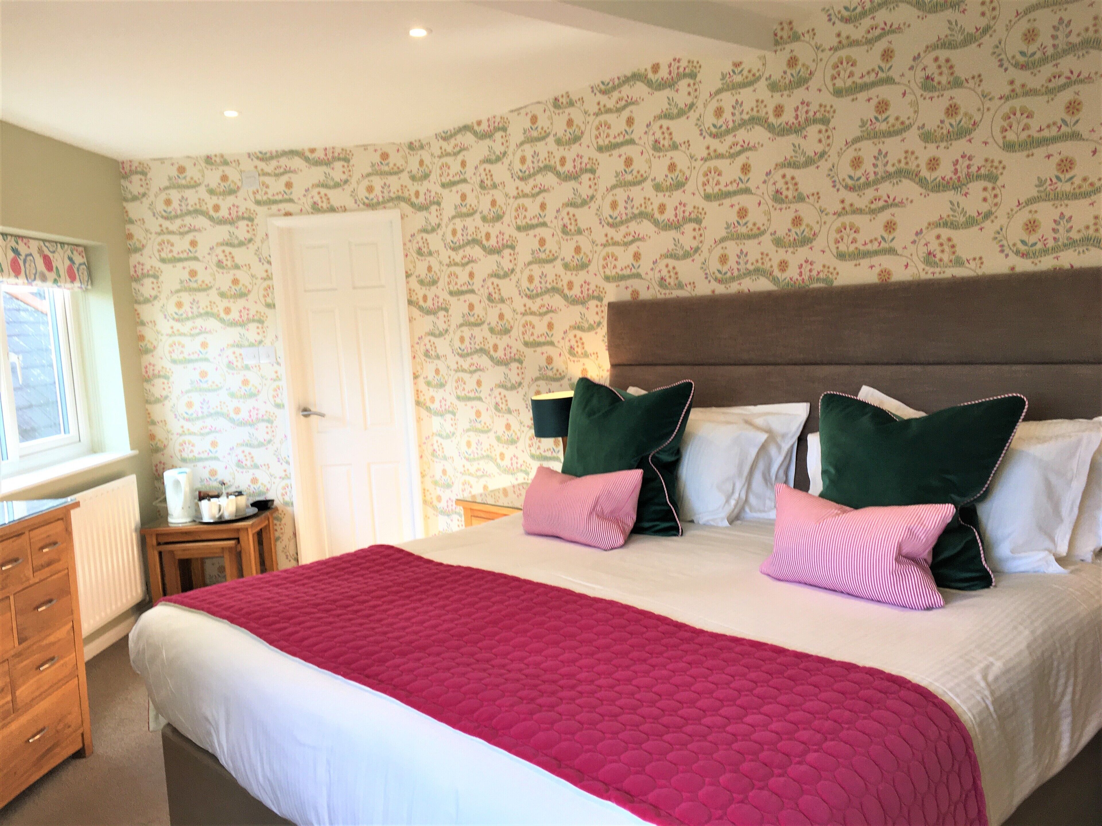 A bedroom with a large bed, a dresser, and a window.