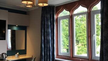 Ein Schlafzimmer mit Bett, Schreibtisch, Stuhl, Kommode und einem Fenster mit Vorhängen.
