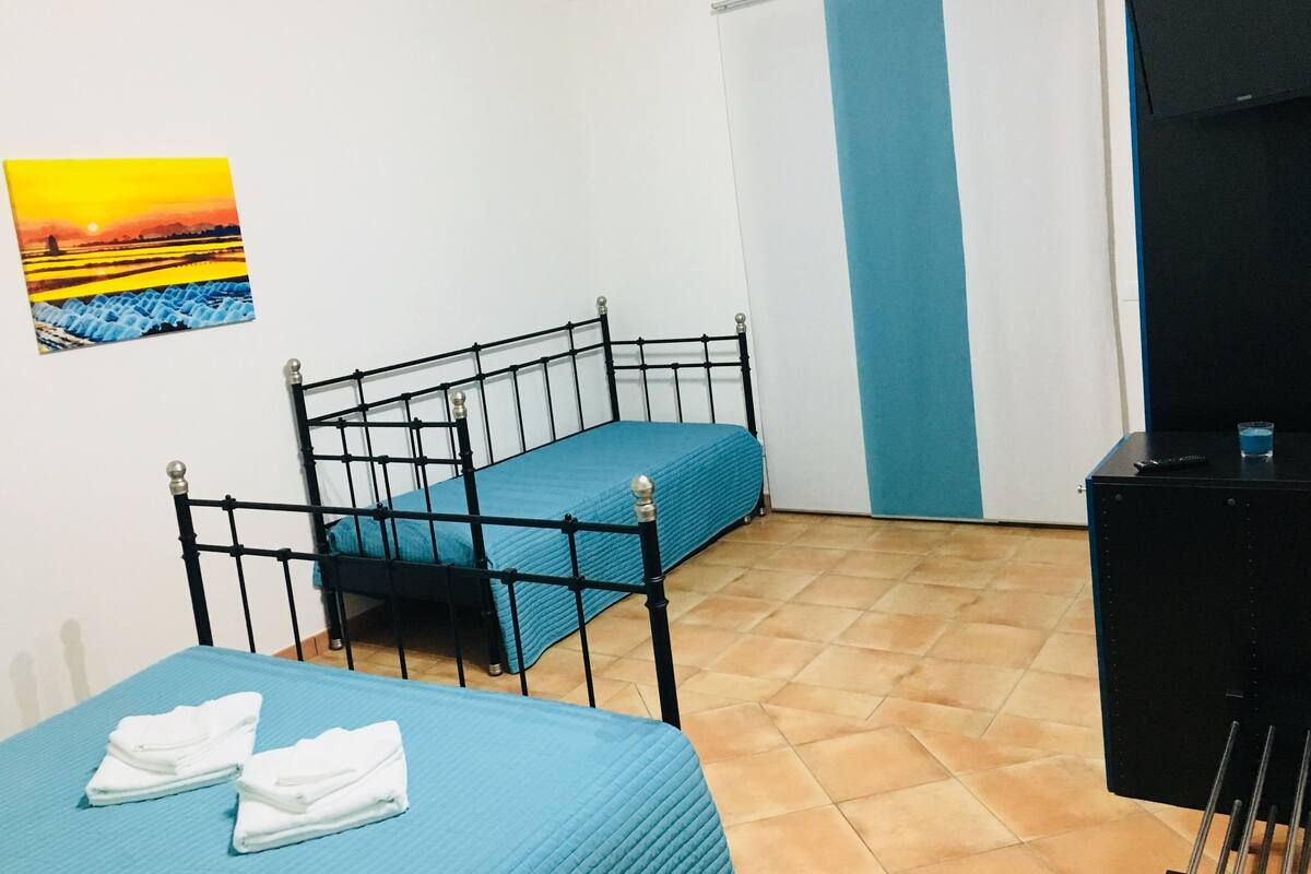 Una habitación con cama, una silla, un escritorio y un cuadro en la pared.