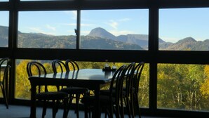 Un comedor con mesa y sillas, ventanas amplias con vista a la montaña.