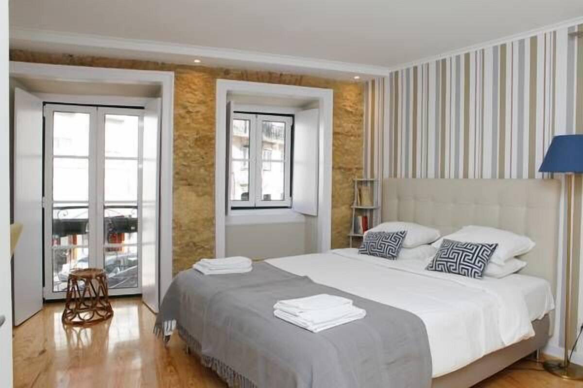 Een slaapkamer met een bed, een raam, een deur en een lamp.
