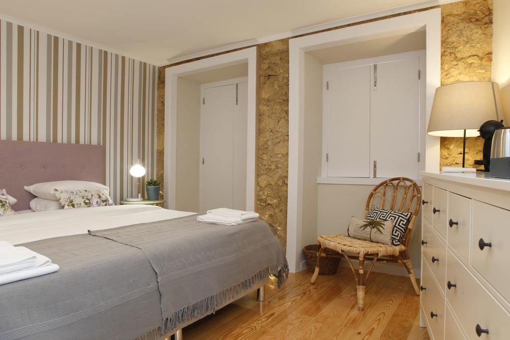 Un dormitorio con cama, una silla, cómoda y lámpara.