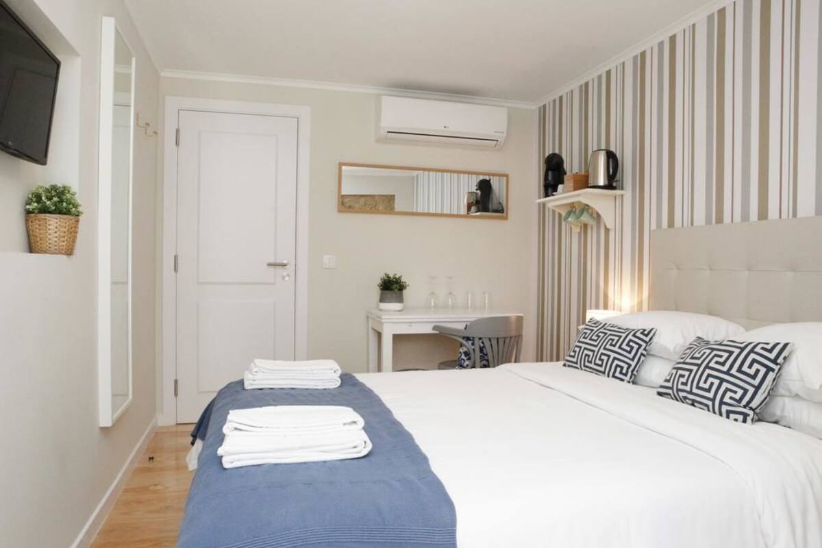 Een netjes ingerichte slaapkamer met een bed, nachtkastje en een klein bureau met stoel.