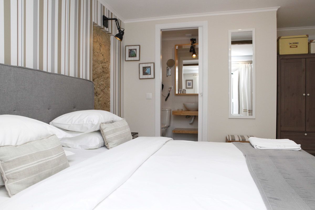 A bedroom with a bed, a headboard, a wardrobe, and a bathroom visible through an open door.