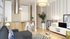 Un salon moderne avec un canapé gris, une table basse, un téléviseur et un coin repas comprenant une table et des chaises blanches.