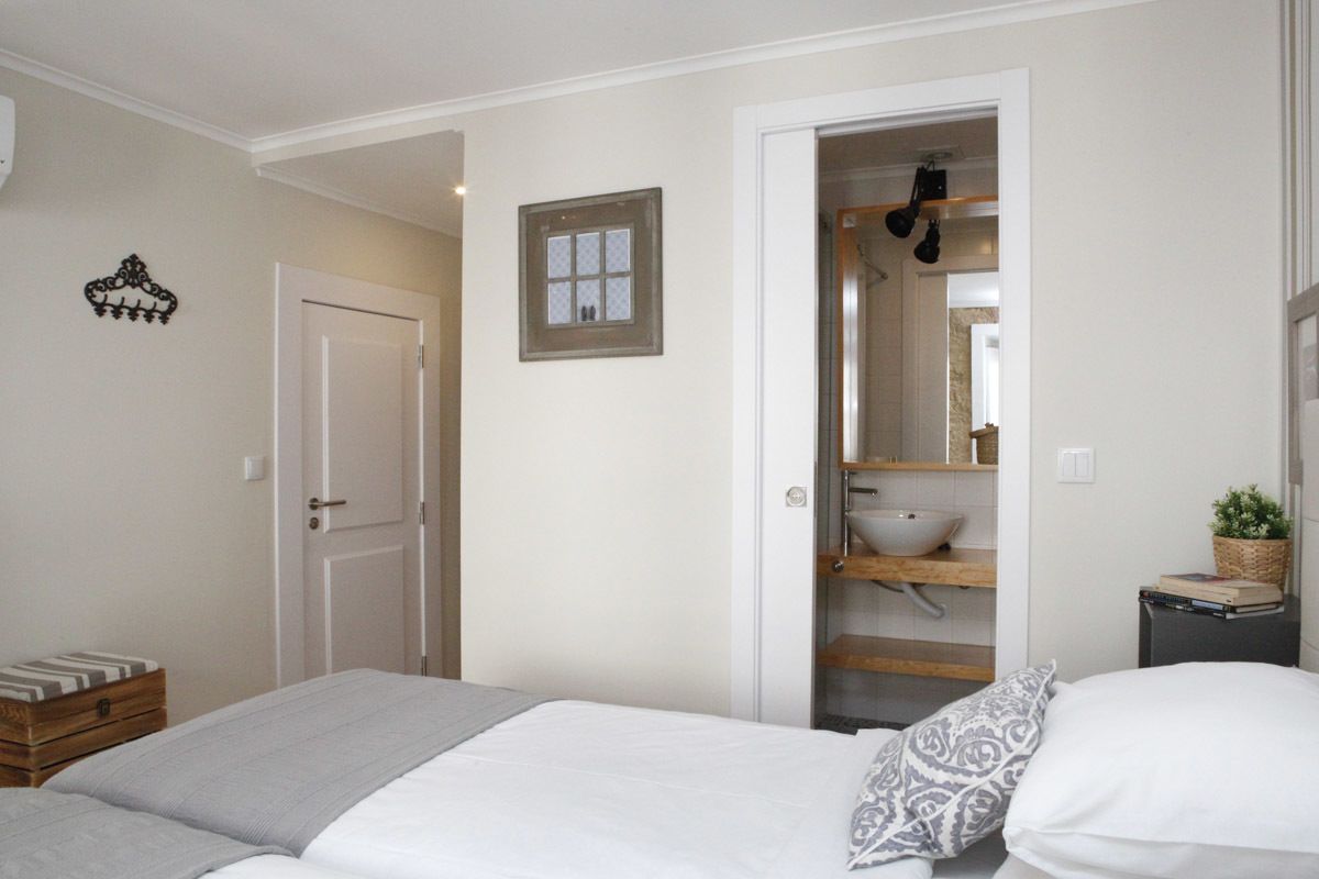 A bedroom with a bed, a bedside table, a wardrobe, and a bathroom visible through an open door.
