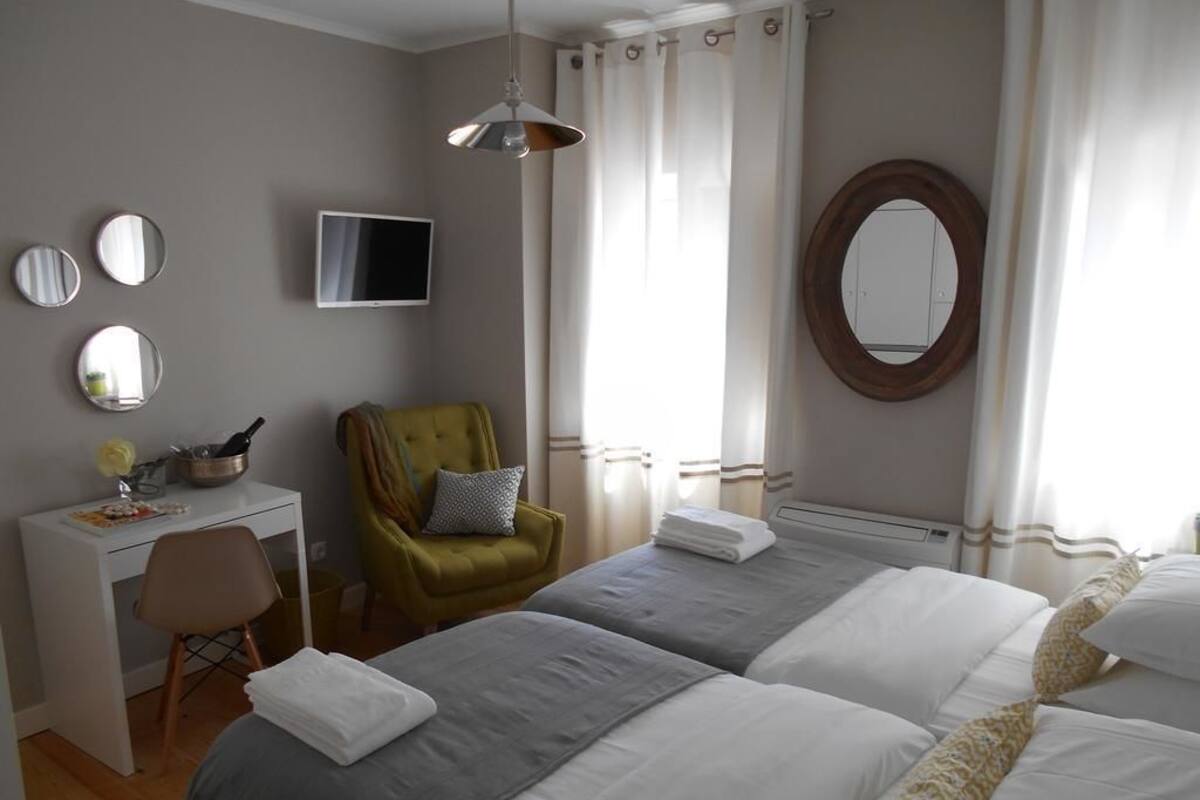 Een hotelkamer met twee bedden, een bureau, een stoel, een televisie en een grote spiegel.