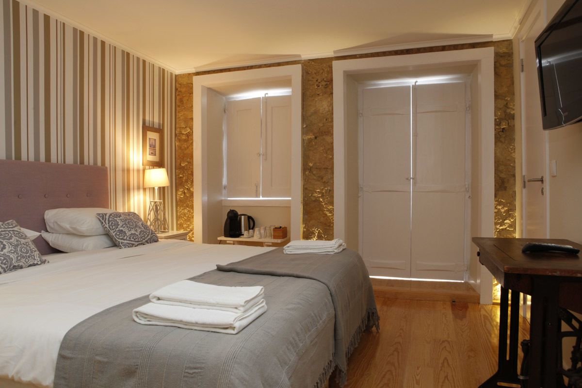 Una habitación de hotel con una cama grande, dos mesitas de noche, un escritorio, un televisor y un armario.