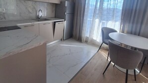 Une cuisine moderne dotée de plans de travail en marbre, d’un four encastré et d’un coin repas avec une table ronde et deux chaises.